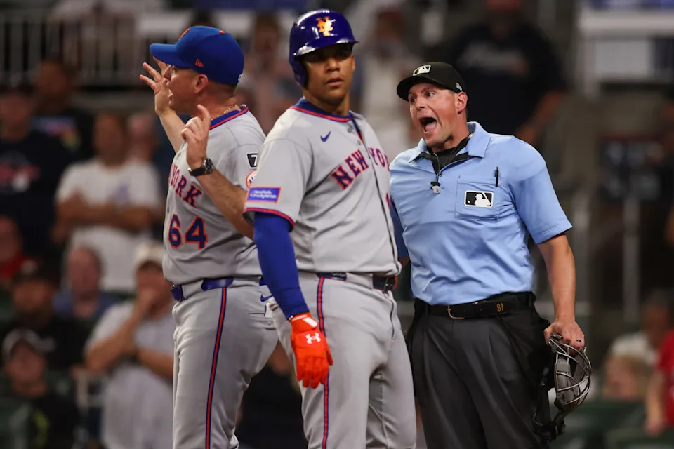 New York Mets right fielder Juan Soto (22) and manager Carlos Mendoza (64) talk to umpire Quinn Wolcott (81) © Brett Davis-Imagn Images