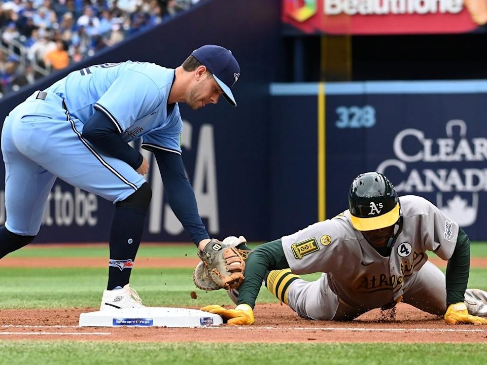  Athletics centre-fielder Denzel Clarke, right, dives safely back into first base ahead of a tag by Toronto Blue Jays first baseman Ernie Clement (22) in fourth inning MLB baseball action in Toronto on Sunday, June 1, 2025.