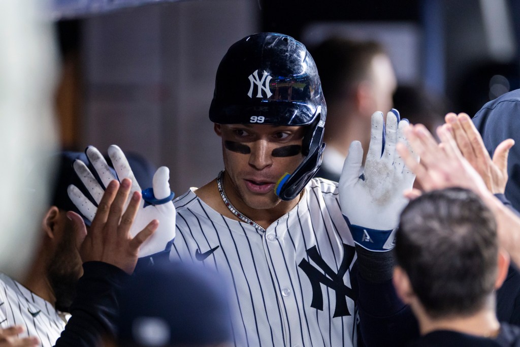 Aaron Judge of the New York Yankees high-fiving teammates in the dugout.