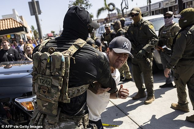 A man is detained as clashes break out after US Customs and Border Protection officers tried to raid a store just south of Los Angeles