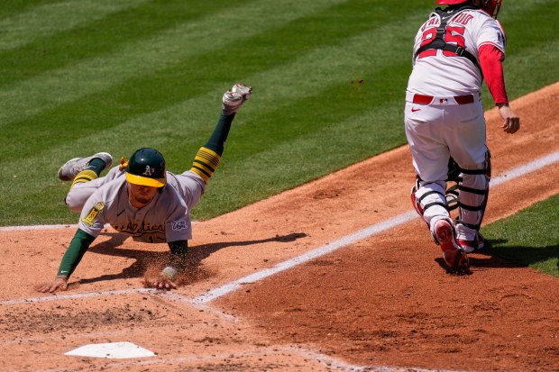 The Athletics’ Luis Urías, left, scores on a sacrifice fly...