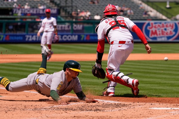 The Athletics’ Luis Urías, left, scores on a sacrifice fly...