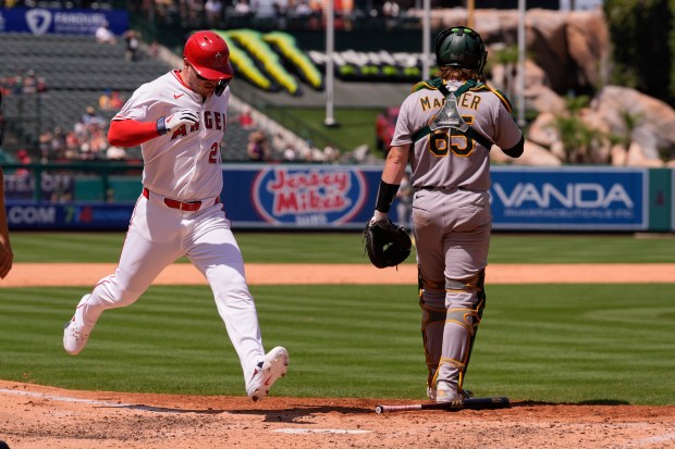 The Angels’ Mike Trout, left, scores on a single by...