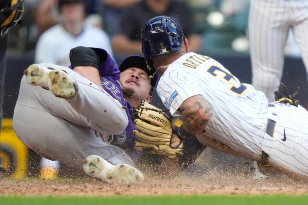 Milwaukee Brewers' Joey Ortiz (3) scores on a wild pitch past a tag by Colorado Rockies' Victor Vodnik, left, during the 10th inning of a baseball game Sunday, June 29, 2025, in Milwaukee. (AP Photo/Aaron Gash)