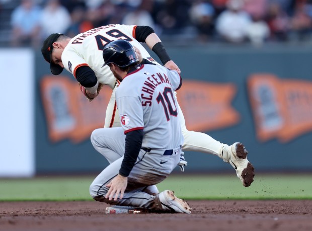 Cleveland Guardians’ Daniel Schneemann #10 is forced out by San...