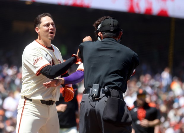 San Francisco Giants’ Wilmer Flores, left, is held back by...