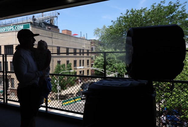Evan Parker and his daughter, Hatten, 5, cool off in front of a mister before a Cubs-Mariners game on June 21, 2025, at Wrigley Field. (John J. Kim/Chicago Tribune)