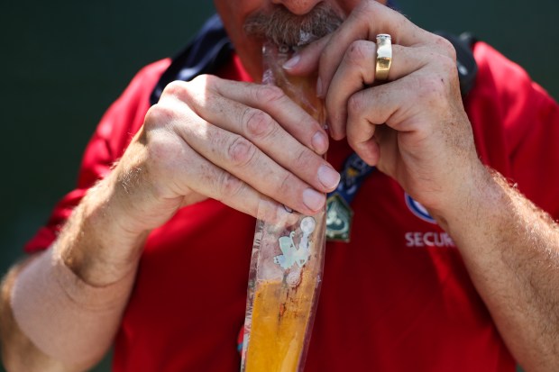 A security worker sucks on a melting ice-pop pouch before a Cubs-Mariners game on June 21, 2025, at Wrigley Field. (John J. Kim/Chicago Tribune)