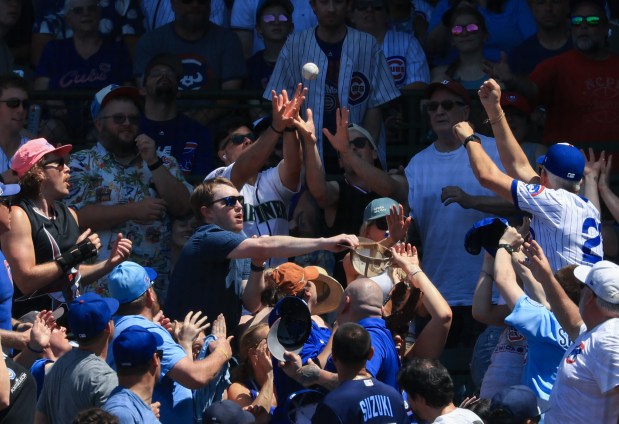 Fans reach for a foul ball in the third inning of a Cubs-Mariners game on June 21, 2025, at Wrigley Field. (John J. Kim/Chicago Tribune)