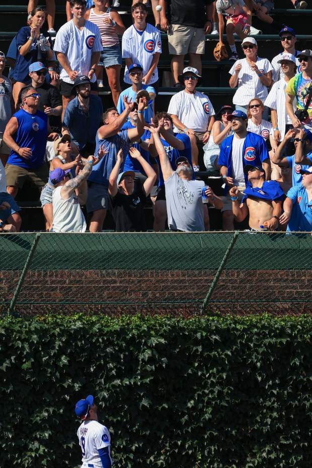 Fans reach for a home run ball hit by Mariners catcher Cal Raleigh in the ninth inning against the Cubs on June 21, 2025, at Wrigley Field. (John J. Kim/Chicago Tribune)