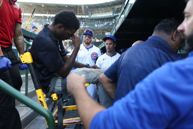 Cubs players and coaches watch as a security worker is transported off the field from being affected by the heat and humidity after a 10-7 Cubs win over the Mariners on June 21, 2025, at Wrigley Field. (John J. Kim/Chicago Tribune)