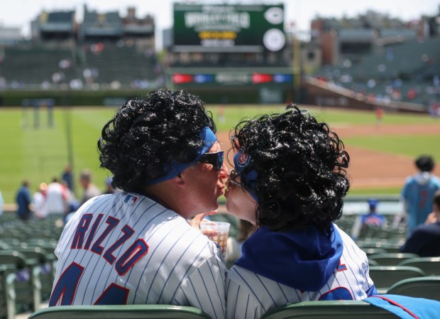 Mike and Jill Lakota, wearing Dansby Swanson hairstyle wigs, kiss during batting practice for a Cubs-Reds game at Wrigley Field on May 31, 2025, in Chicago. (John J. Kim/Chicago Tribune)