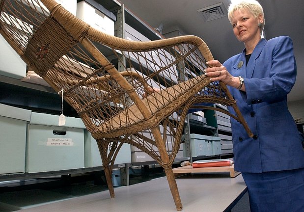 Barbara Hanson, coordinator of the archives for United Airlines, holds up a wicker chair in 2003, that served as passenger seating in 1928. The archives were stored at the corporate headquarters for the airline in Elk Grove Village. (George Thompson/Chicago Tribune)