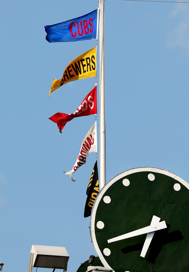 The National League Central standings are reflected in the order of flags flying atop the Wrigley Field scoreboard, with the Cubs in first place and the Brewers in second, before a game between the teams Tuesday, June 17, 2025. (Chris Sweda/Chicago Tribune)