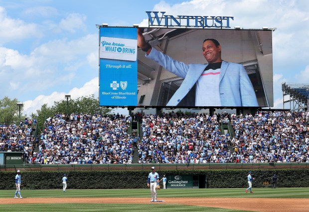 Cubs players warm up for the third inning while former...