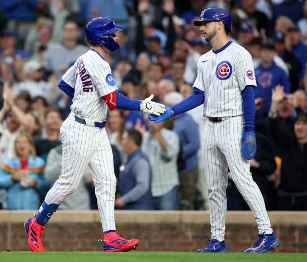 Cubs center fielder Pete Crow-Armstrong, left, slaps hands with Kyle Tucker after hitting a two-run home run in the fourth inning against the Pirates on June 12, 2025, at Wrigley Field. (Chris Sweda/Chicago Tribune)