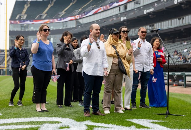 Lazaro Sanchez, center, who grew up in Spain, and 24 other new American citizens take the naturalization oath Thursday, June 5, 2025, during a ceremony on Rate Field before the White Sox faced the Tigers. Judge Matthew F. Kennelly performed the ceremony. (Brian Cassella/Chicago Tribune)