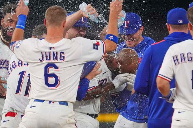 Rangers right fielder Adolis García, center right, covers his face as teammates douse him after his RBI singled scored the winning run in the 11th inning of a 5-4 victory over the White Sox on Saturday, June 14, 2025, in Arlington, Texas. (LM Otero/AP)