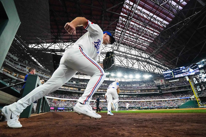 Texas Rangers outfielder Wyatt Langford and first baseman Jake Burger (21) take the field...