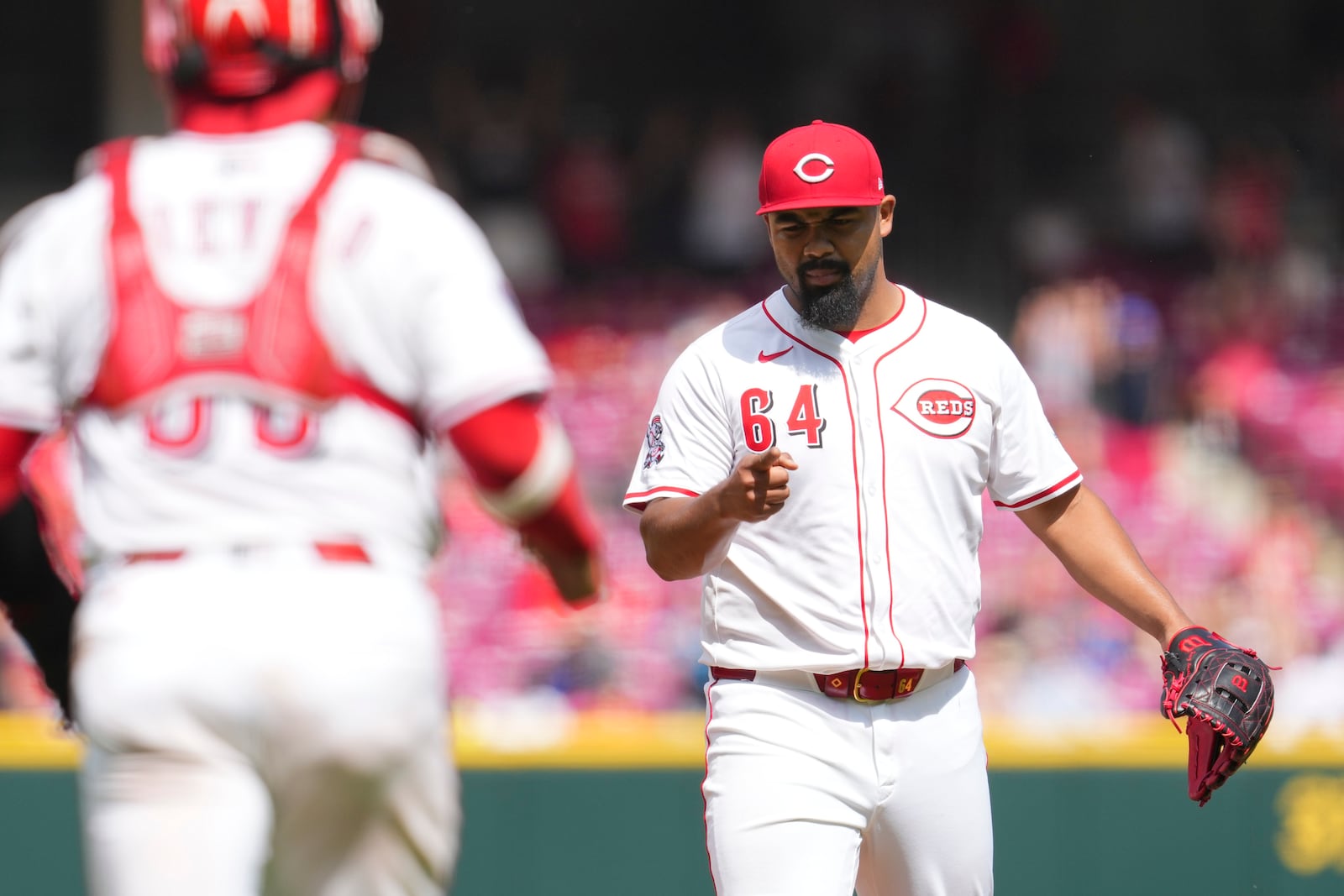 Cincinnati Reds' Tony Santillan (64) gestures to teammate Jose Trevino (35) following a baseball game against the Arizona Diamondbacks, Sunday, June 8, 2025, in Cincinnati. (AP Photo/Jeff Dean)