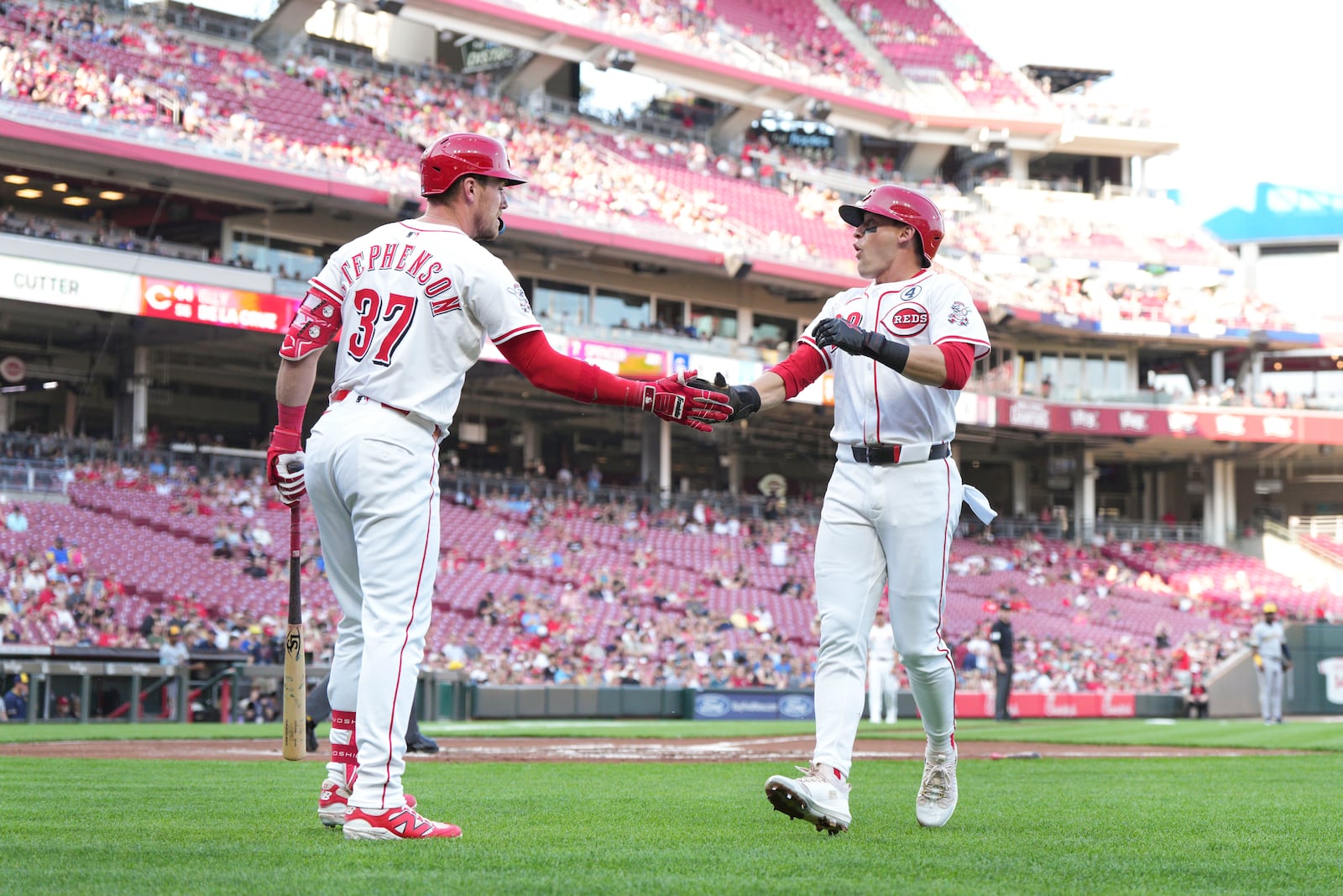 Cincinnati Reds' TJ Friedl (29) celebrates with teammate Tyler Stephenson (37) after scoring on a single hit by Elly De La Cruz during the first inning of a baseball game against the Milwaukee Brewers, Monday, June 2, 2025, in Cincinnati. (AP Photo/Jeff Dean)