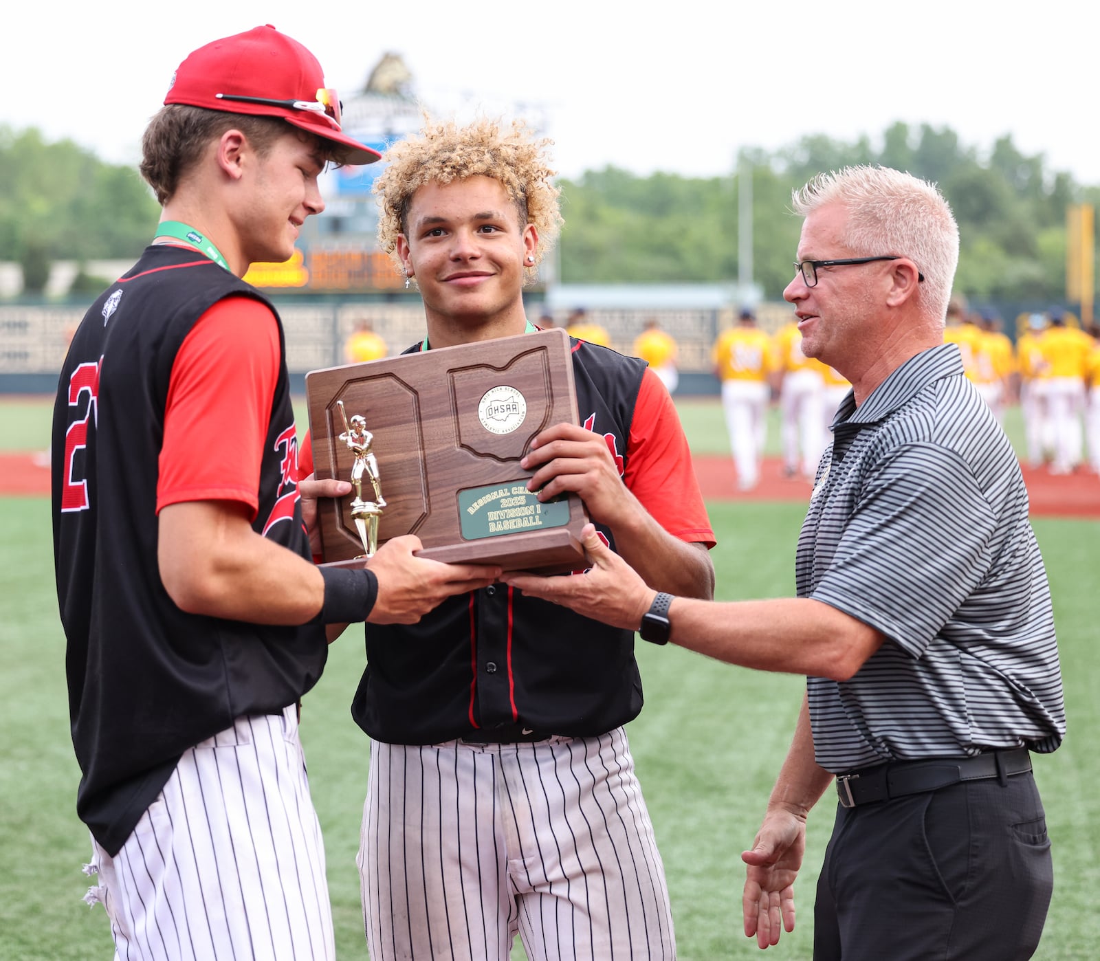 Lakota West senior Landon Holt (left) and junior Braydon Johnson are presented a regional championship trophy by Wright State employee and OHSAA representative Chris Bethel after defeating Cincinnati Moeller 3-2 on Wednesday at Nischwitz Stadium. BRYANT BILLING / STAFF