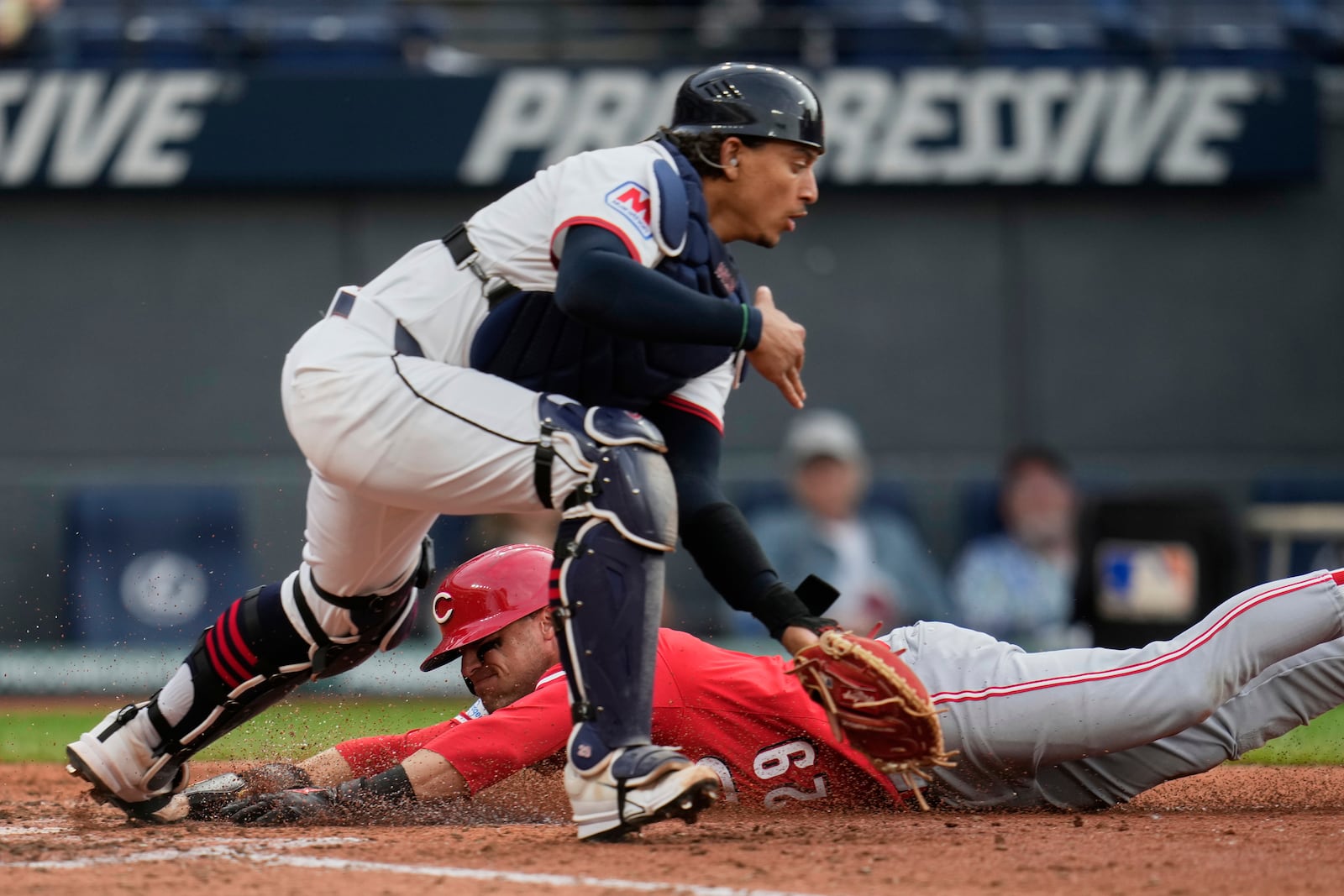 Cincinnati Reds' TJ Friedl, rear, slides safely behind Cleveland Guardians catcher Bo Naylor, front, to score in the fifth inning of a baseball game in Cleveland, Monday, June 9, 2025. (AP Photo/Sue Ogrocki)