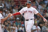 Boston Red Sox's Rafael Devers, right, is all smiles as he heads to the dugout after after...