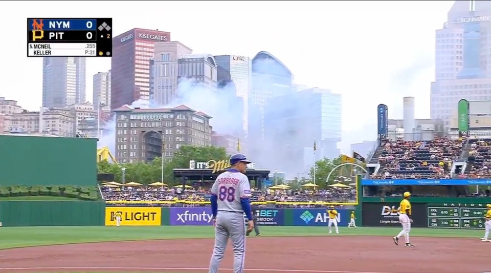 Baseball game in progress with smoke in the background.
