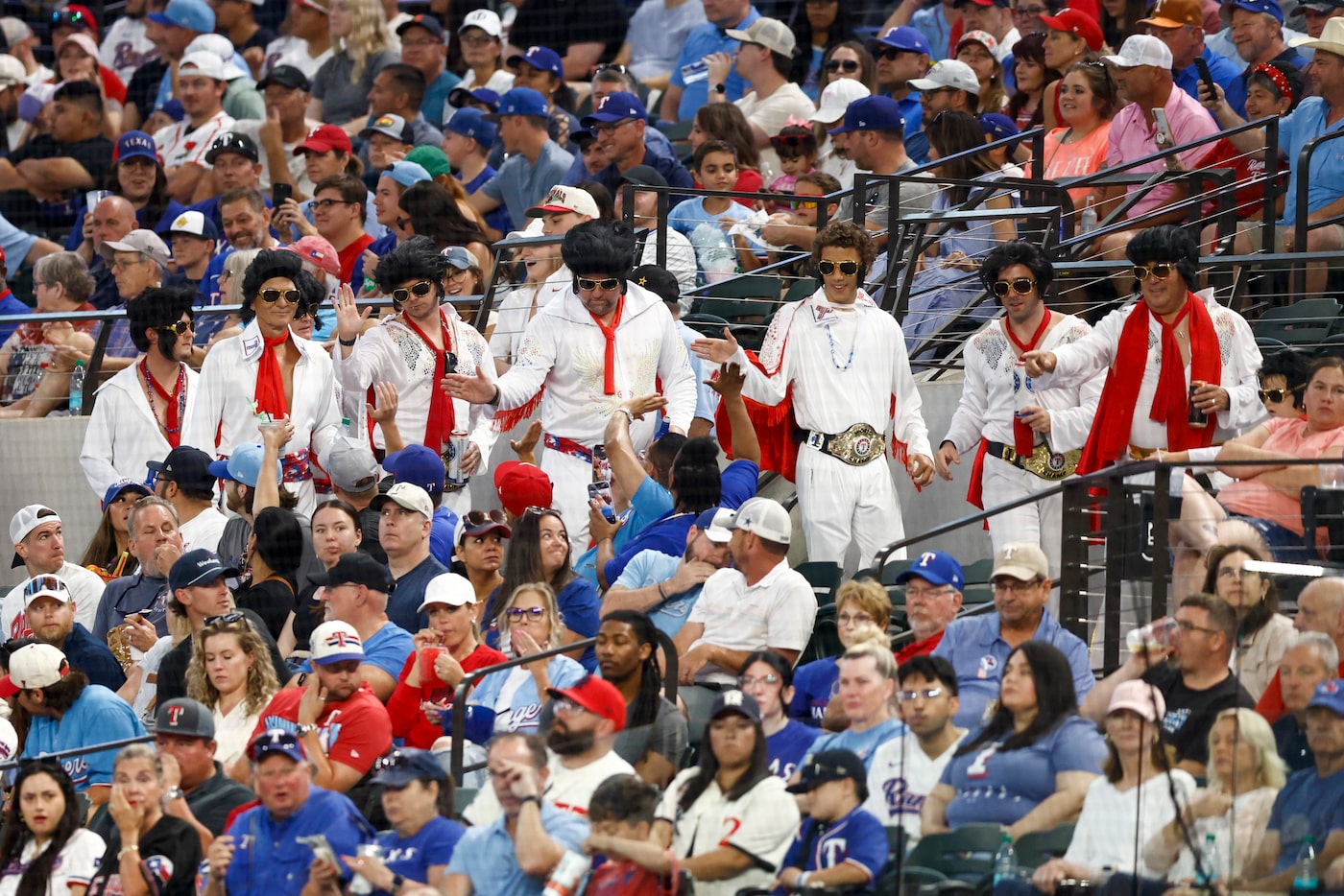 A large group of Texas Rangers fans dressed as Elvis Presley walk around the lower concourse...