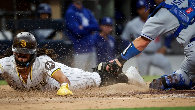 San Diego Padres' Fernando Tatis Jr. slides safely across home against Los Angeles Dodgers' Dalton Rushing during the third inning at Petco Park on Tuesday, June 10, 2025 in San Diego, CA. (Meg McLaughlin / The San Diego Union-Tribune)