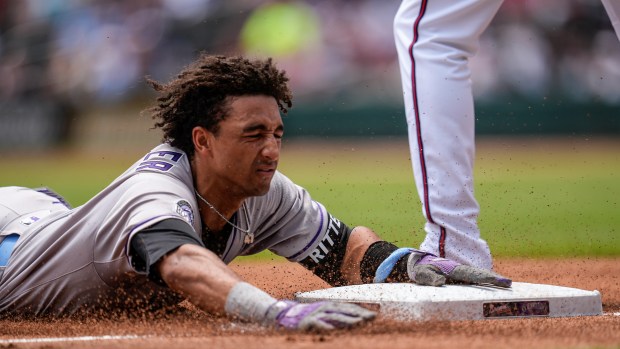 Colorado Rockies shortstop Ryan Ritter (8) slides into third base on errors after bunting against the Atlanta Braves in the third inning inning of a baseball game, Sunday, June 15, 2025, in Atlanta. (AP Photo/Mike Stewart)