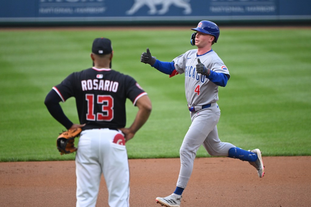 Chicago Cubs player Pete Crow-Armstrong celebrates a home run as a Washington Nationals player looks on.