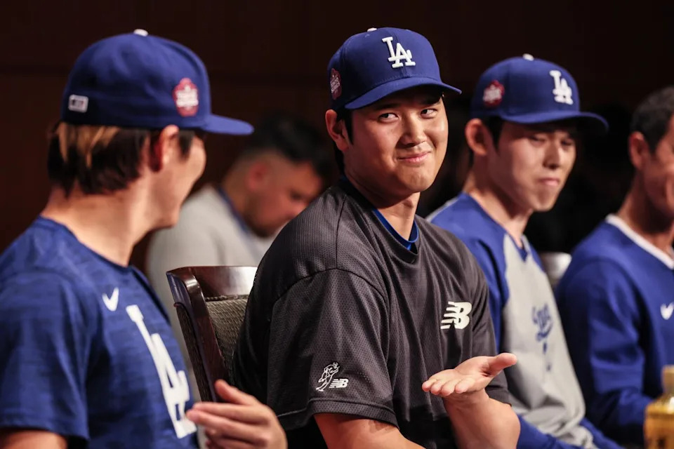 Shohei Ohtani, center, gestures to Yoshinobu Yamamoto, left, as Roki Sasaki, right, looks on during a press conference.