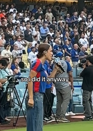Woman singing national anthem at baseball game.