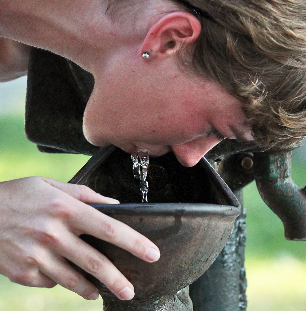 A look at high school cross country runners training in this summer’s high heat and humidity. The Blake cross country team met at Lake Harriet to head out on a training run, with an emphasis on captain Clare Flanagan. Flanagan drank at a water pump to sta
