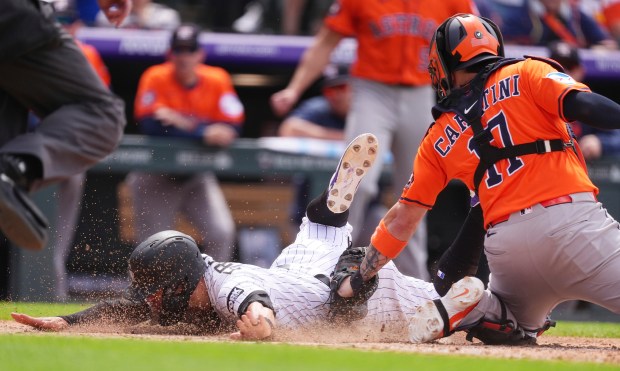 Houston Astros catcher Victor Caratini, right, tags out Colorado Rockies' Tyler Freeman as he tries to score on triple hit by pinch-hitter Miceky Moniak in the seventh inning of a baseball game, Thursday, July 3, 2025, in Denver. (AP Photo/David Zalubowski)