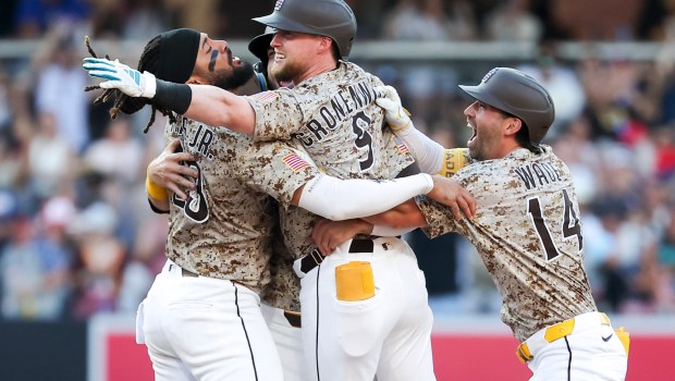 Jake Cronenworth #9 of the San Diego Padres is congratulated by Fernando Tatis Jr. #23, Gavin Sheets #30 and Tyler Wade #14after hitting a walk-off single against the Texas Rangers during the tenth inning at Petco Park on Friday, July 4, 2025 in San Diego, CA. (Meg McLaughlin / The San Diego Union-Tribune)