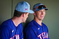 Texas Rangers outfielders Wyatt Langford (right) and Evan Carter laugh in the dugout before...
