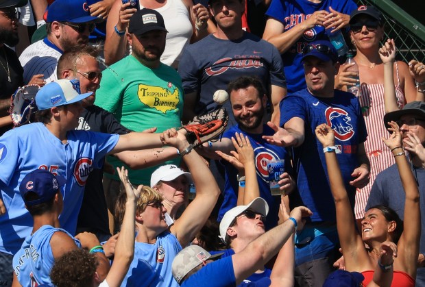 Fans reach for a tossed ball from Cubs center fielder...