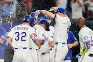 Texas Rangers' Marcus Semien, center, is congratulated by teammates after hitting a...