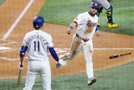 Texas Rangers Jake Burger (right) points to teammate Kyle Higashioka (11) after scoring on a...