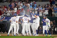 The Texas Rangers celebrate after a run-scoring single by Marcus Semien in the 10th inning...