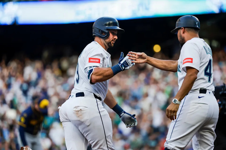 Mariners catcher Cal Raleigh is congratulated by third base coach Kristopher Negrón after hitting a solo homer in the sixth inning for the only run of the game against the Brewers on July 22 at T-Mobile Park.