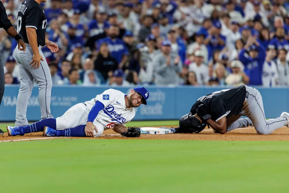Dodger Max Muncy grimaces as he holds his left knee after colliding with White Sox outfielder Michael A. Taylor.