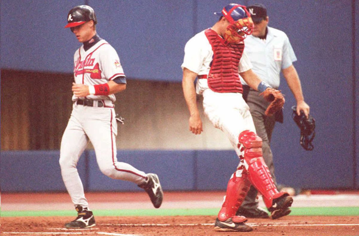 The Braves’ Chipper Jones (L) scores after hitting