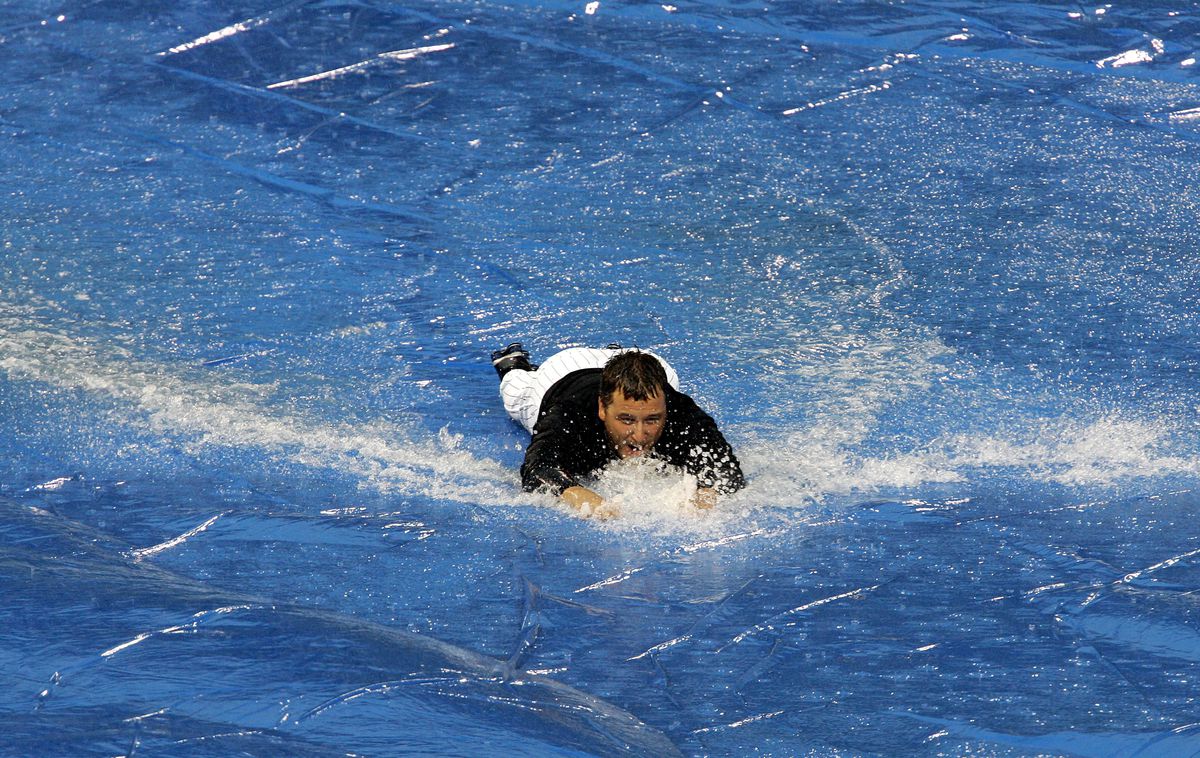 Pitcher Mark Buehrle #56 of the Chicago White Sox slides across the tarp during a rain delay of a game between the White Sox and the Detroit Tigers on July 20, 2005 at U.S. Cellular Field in Chicago, Illinois. The Tigers defeated the White Sox 8-6.