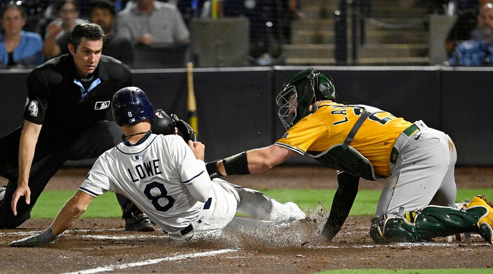 Tampa Bay Rays' Brandon Lowe (8) is tagged out at home by Athletics catcher Shea Langeliers, right, during the eighth inning of a baseball game Monday, June 30, 2025, in Tampa, Fla. (AP Photo/Jason Behnken)
