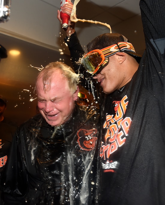 Baltimore Orioles manager Buck Showalter is doused with beer by Manny Machado in the visitors' clubhouse after the Orioles defeated the New York Yankees 5-2 in a baseball game to go to the playoffs , Sunday, Oct. 2, 2016, in New York.