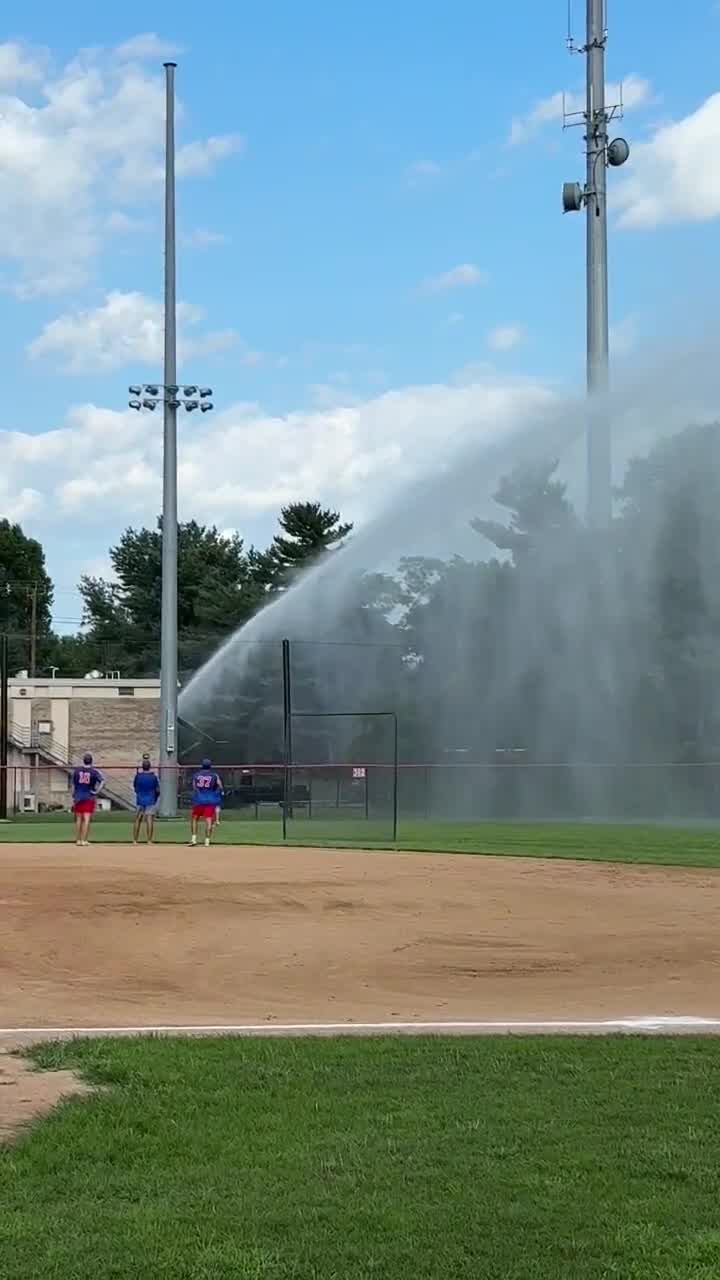 Firefighter sprays baseball field after stray ball hits car